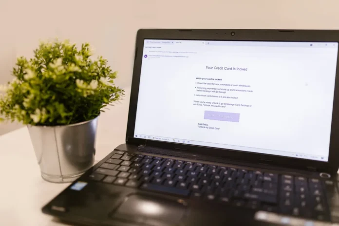 Écran d'interface bancaire en ligne avec champ IBAN, main hésitante au clavier, documents et téléphone sur un bureau
