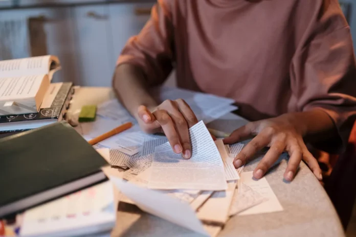 Élève concentré à son bureau entouré de fiches de révision et de livres, prêt à commencer un examen écrit