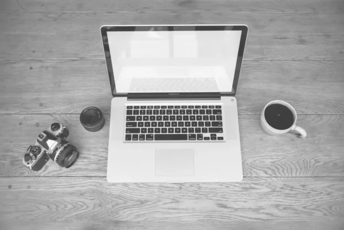 Employé travaillant à son bureau avec caméra de surveillance visible en arrière-plan dans un open space