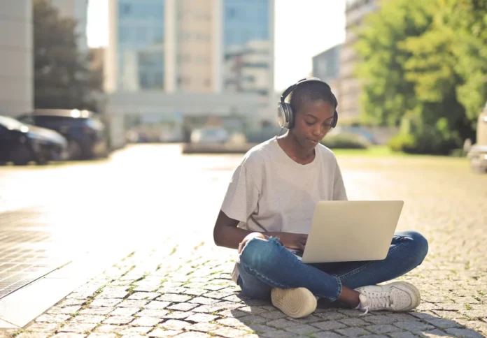 Personne suivant une formation en ligne sur ordinateur avec casque et carnet de notes