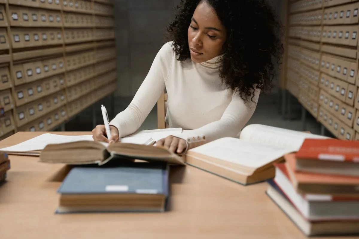 Étudiant lisant des sources académiques et prenant des notes structurées pour son mémoire