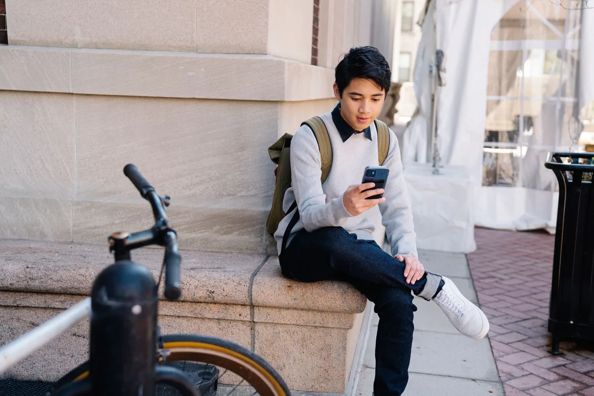 Étudiant suivant un cours en visioconférence sur son téléphone portable