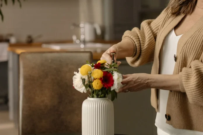 Mains arrangeant des fleurs colorées et du feuillage sur un plan de travail avec outils de fleuristerie.