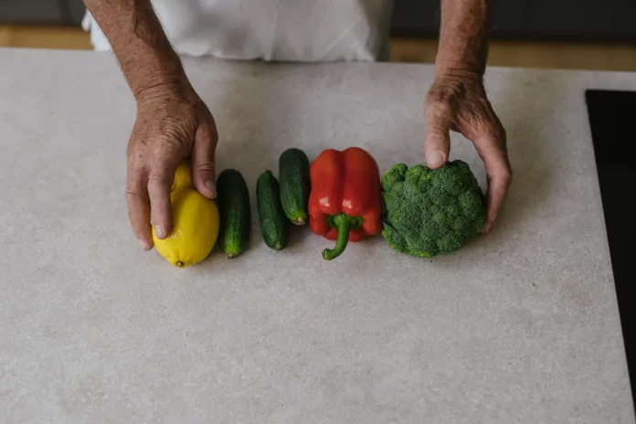 Mains préparant des légumes frais et produits de cuisine professionnelle sur un plan de travail