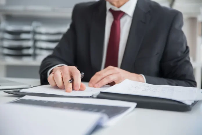 Mains de parent tenant la main d'un nouveau-né près de documents administratifs et d'un calendrier