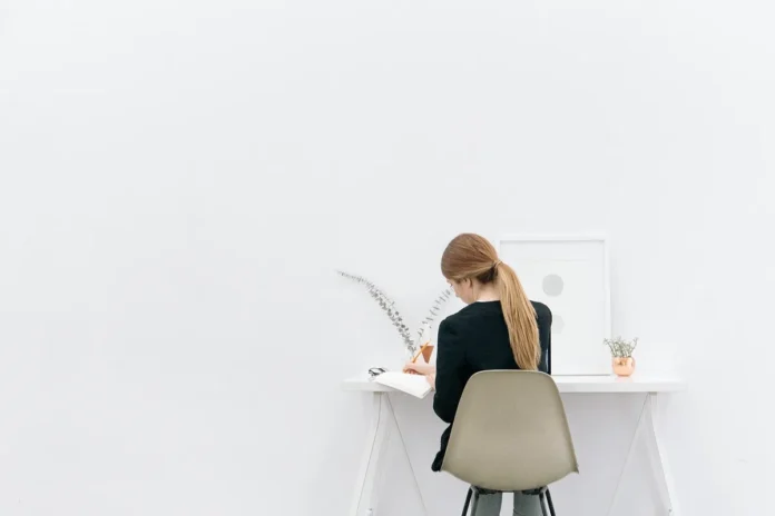 Coin de bureau en plein jour avec une tasse, une plante et une chaise tournée vers la fenêtre