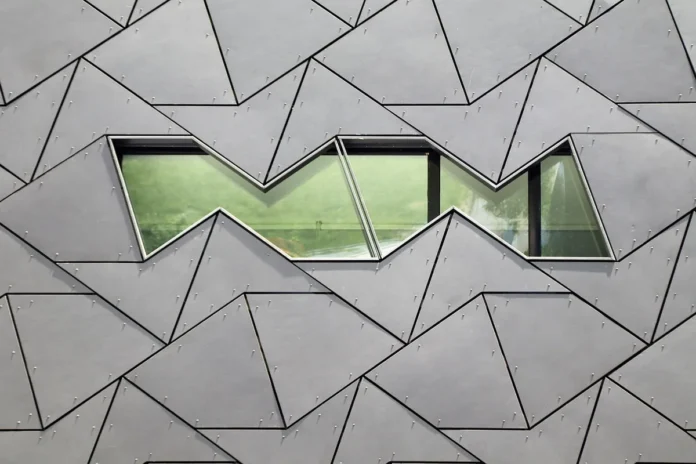 Bureau d'architecte avec plans, matériaux durables et écran d'ordinateur affichant un modèle 3D de bâtiment