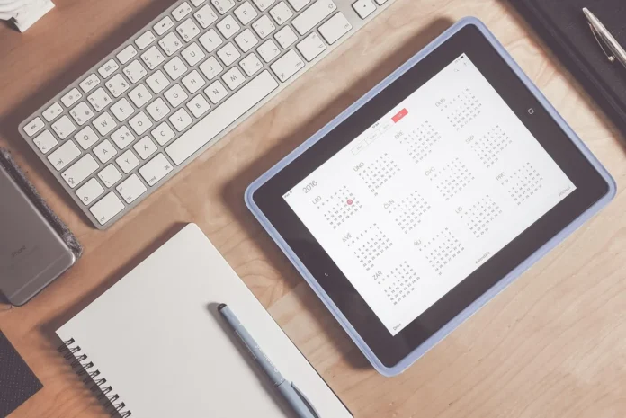 Mains anonymes posant un plateau et un calendrier sur une table de cuisine