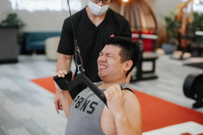 Un coach sportif corrigeant la technique d'exercice d'un client en salle de sport