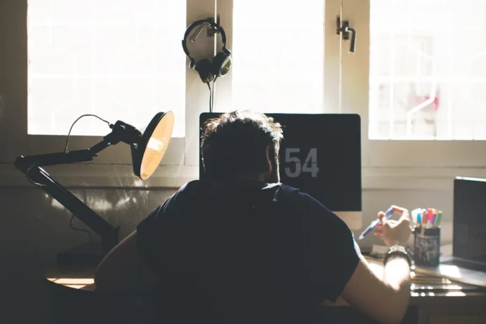 Personne étudiant à distance sur un ordinateur portable avec des documents et des notes sur un bureau à domicile