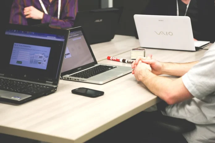 Deux professionnels en entretien d'évaluation, l'un prenant des notes tandis que l'autre s'exprime