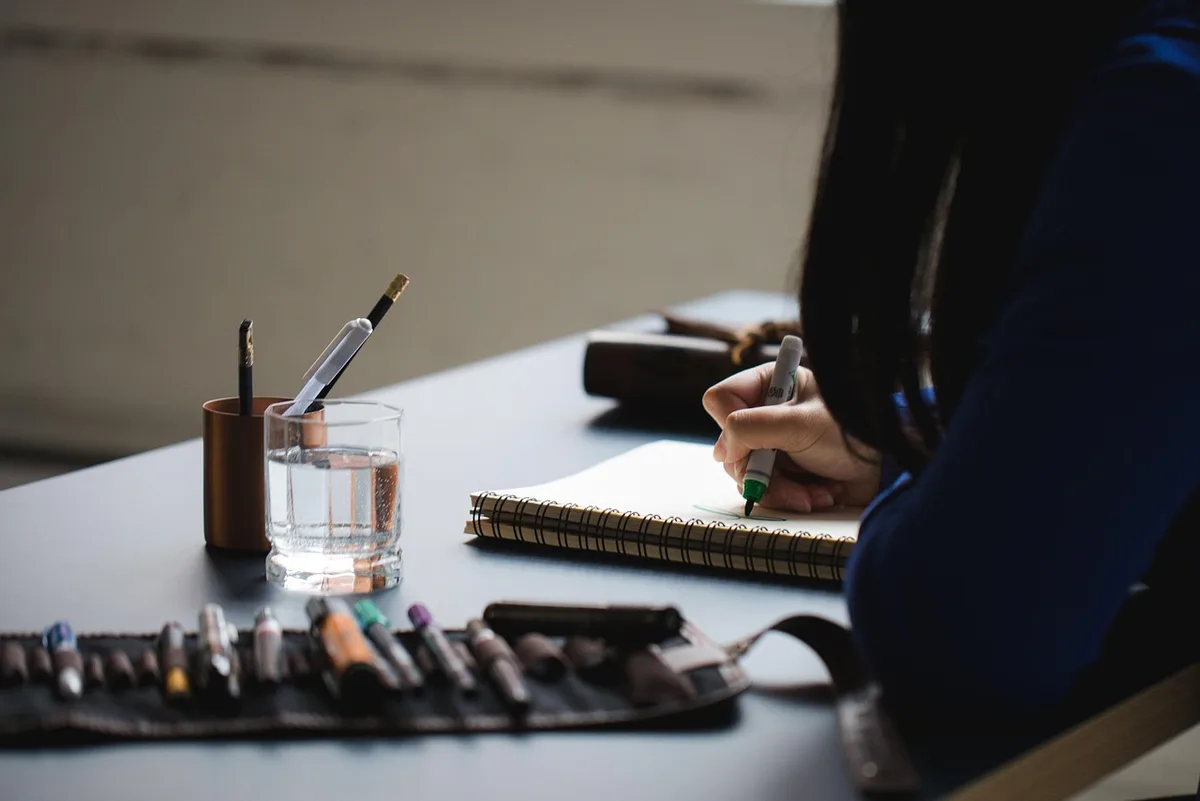 Personne écrivant des objectifs dans un carnet sur un bureau lumineux
