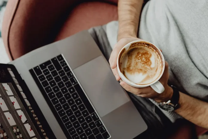 Des collègues discutent autour d'une table avec des tasses de café dans un environnement de bureau ouvert.
