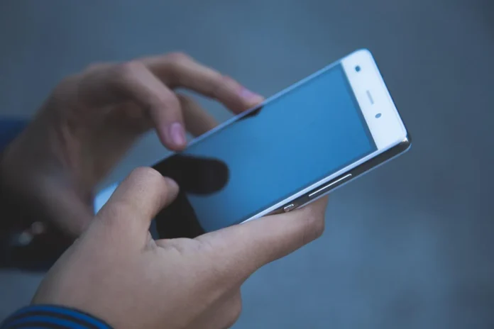 Smartphone et carnet avec graphiques flous sur table en bois, mains anonymes en arrière‑plan