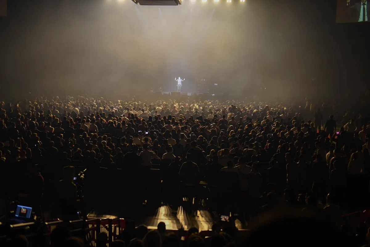 Petite foule devant une scène en plein jour lors d'un festival local