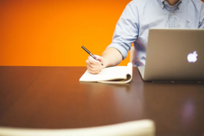 Table de formation en journée avec portable, carnet et mains prenant des notes