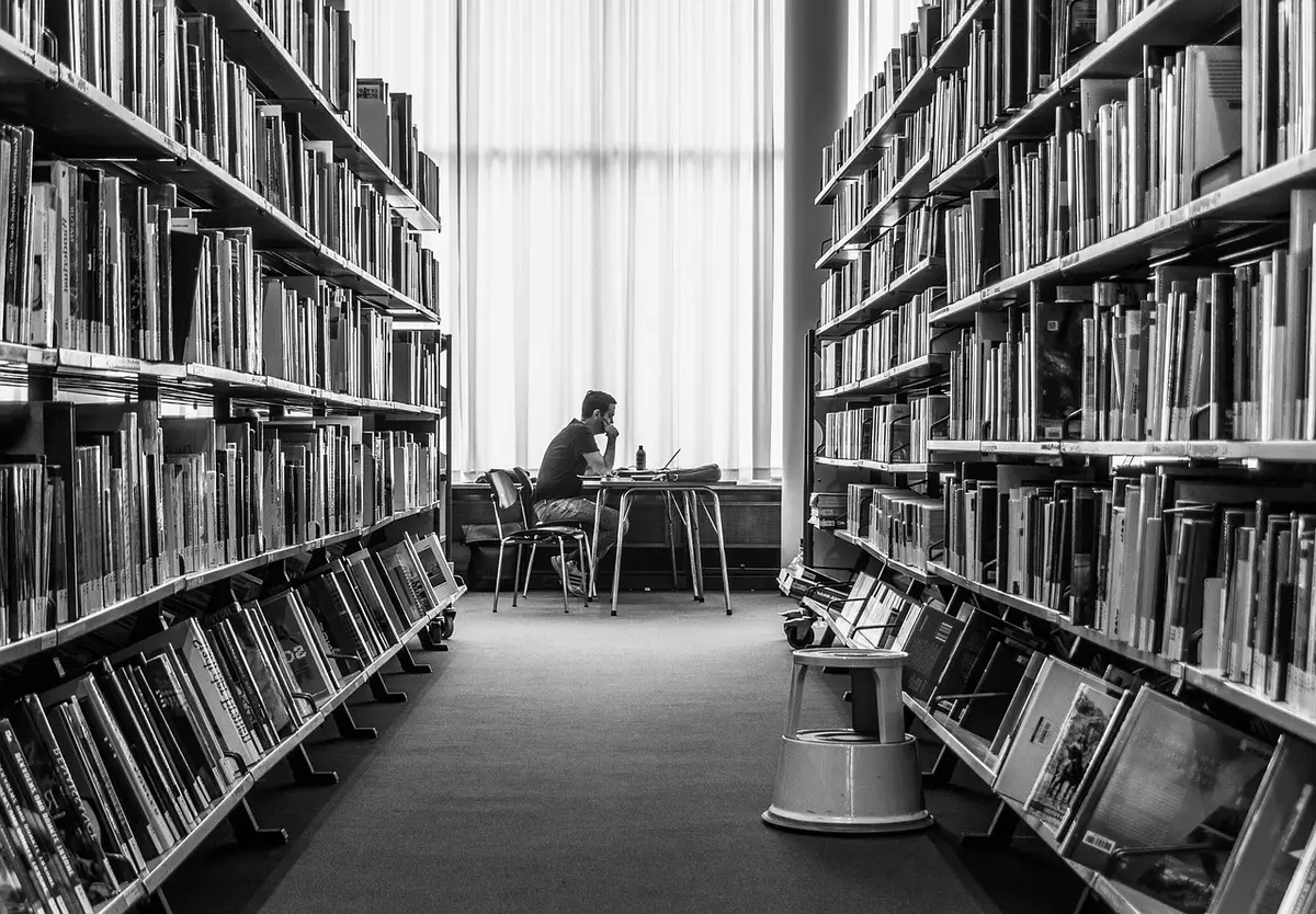 Étudiant dans une bibliothèque universitaire examinant des livres de musicologie