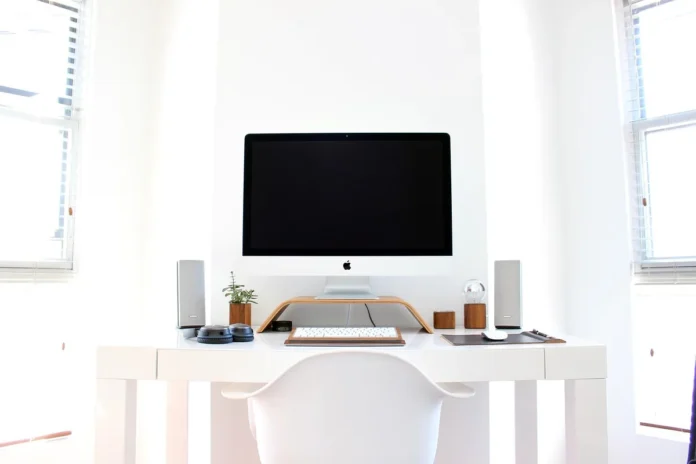 Bureau lumineux avec ordinateur portable, casque et bloc-notes près d'une fenêtre en journée