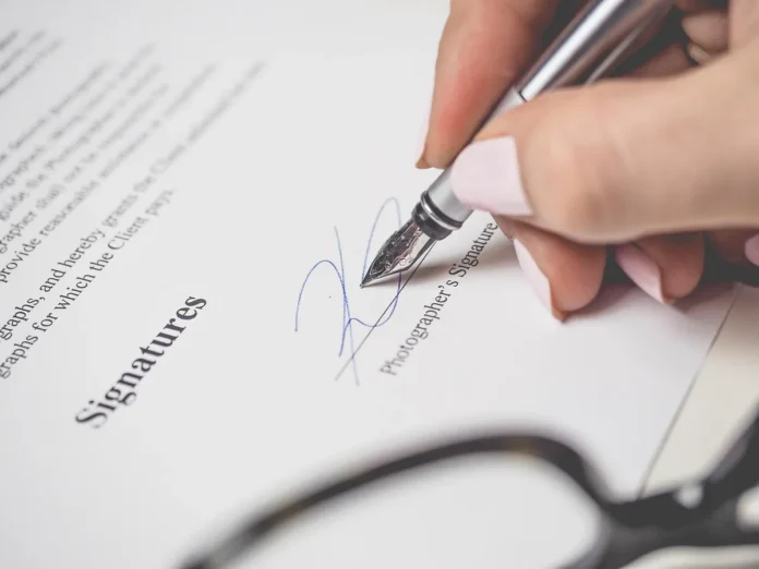 Contrat signé posé sur une table en bois, stylo et maillot flou en arrière-plan