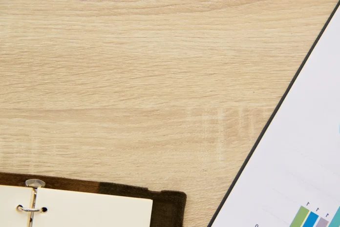 Planificateur marketing sur une table de bureau avec calendrier, ordinateur portable et mains indiquant des dates