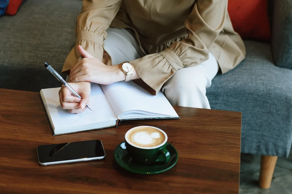 Personne prenant des notes et rassemblant preuves sur une table de réunion en journée
