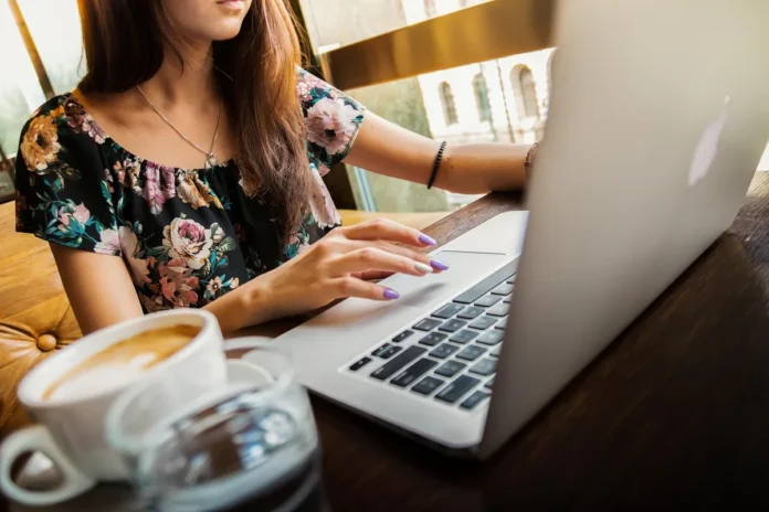 Main anonyme triant des étiquettes produit sur une table claire près d'une fenêtre
