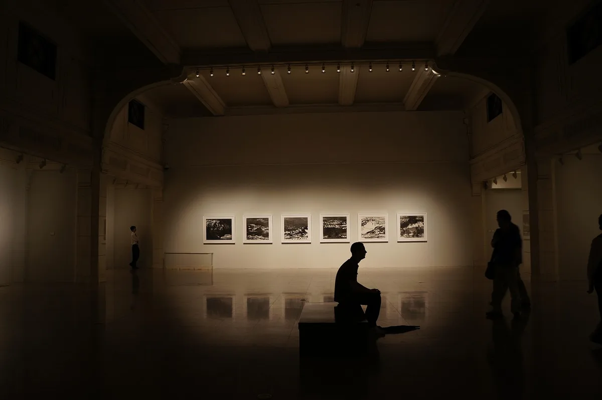 Intérieur de galerie d'art montrant des œuvres exposées et des visiteurs en journée